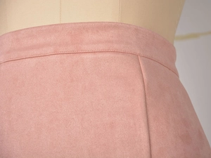 Détail de la texture en daim rose avec coutures à la taille et fermeture éclair