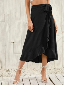 Detail of a black wrap skirt featuring an elegant side tie bow and ruffled hemline