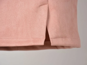Détail d'une jupe en daim rose poudré avec fente latérale et double surpiqûre soignée