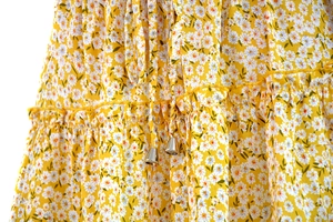 Close-up of yellow floral skirt fabric with white daisies and drawstring metal aglets