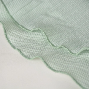 Detailed view of mint green ribbed fabric with ruffle lettuce edge stitching on the hem