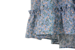 Detail of light blue floral skirt featuring double-layered ruffle hem and delicate prints