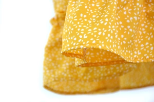 Detail of high-waist yellow floral skirt featuring neat edge stitching and light fabric