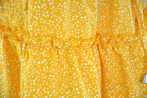 Detail of ginger floral chiffon fabric with ruffled edges and drawstring metal tips