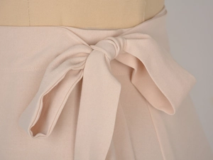 Detail of light pink chiffon wrap skirt featuring an elegant bow tie waist design