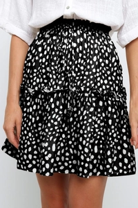 Détail d'une jupe courte noire à fleurs taille haute avec volants et motif à pois