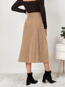Macro shot of khaki corduroy fabric texture and high-waisted A-line hem on long skirt