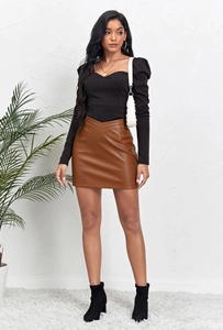 Détail d'une jupe courte tendance en similicuir marron avec un haut noir à manches longues