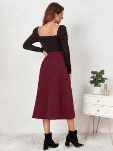 Detail view of the wine red corduroy skirt's texture and A-line back fit on a model