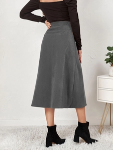 Rear view of a grey corduroy high waist midi skirt paired with black ankle boots