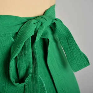 Detailed close-up of vibrant green crepe fabric texture and side-tie waist knot detail