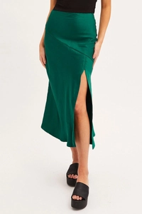 Detail of deep green satin midi skirt showing high waist and elegant side slit design