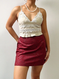 Détail d'une mini-jupe jacquard rouge avec un caraco en dentelle crème pour femme