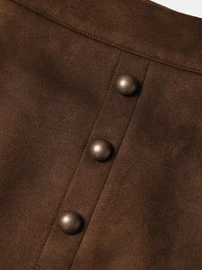 Détail d'une jupe en daim avec trois boutons métalliques vintage disposés verticalement