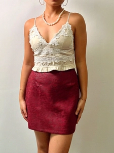Détail de la dentelle du caraco blanc et texture jacquard bordeaux de la mini-jupe