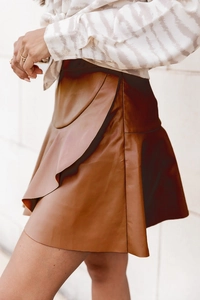 Détails d'une mini-jupe en similicuir marron à taille haute avec volants sur le côté
