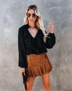 Détail d'une jupe en similicuir caramel à taille haute avec ourlet à volants