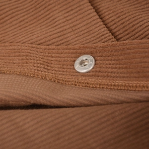 Close-up of brown corduroy fabric texture and silver metal snap button on high waist skirt