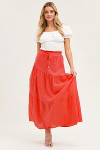 Détail de la jupe longue rouge corail en coton et lin avec volants et taille à cordon coulissant