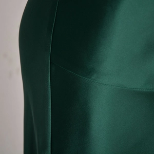 Detailed close-up of dark green satin fabric showing smooth texture and stitching