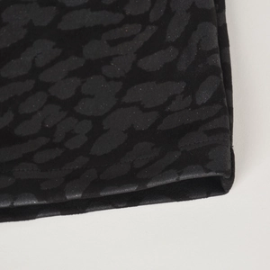 Détail de la jupe en daim noir avec texture léopard brillante et coutures précises