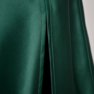 Macro shot of high-quality stitching and glossy satin texture on green high-waist skirt