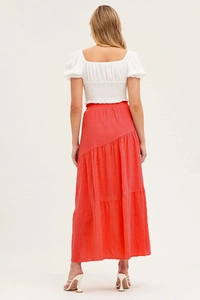 Détail d'une jupe longue à volants en coton corail avec coutures asymétriques et haut chic