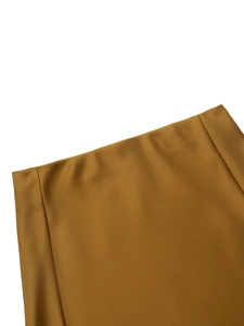 Détail de la jupe en satin bronze montrant la texture lisse et les coutures soignées