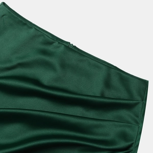 Détail macro d'une jupe en satin vert foncé montrant la texture lisse et le zip invisible