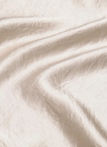 Detailed close-up of champagne satin fabric showing soft wrinkles and pearlescent luster