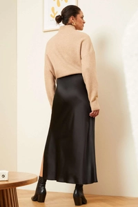 Detail view of a black satin midi skirt with elegant luster and high-quality drape finish