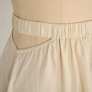 Detailed view of elastic gathered waist with chic V-cut side hollow on beige skirt