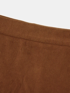 Detailed macro shot of brown corduroy fabric texture and stitching on the high waist skirt