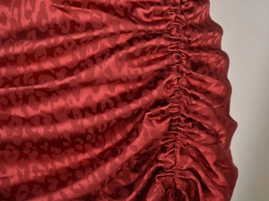 Détail du satin jacquard léopard rouge foncé avec une élégante texture froncée latérale