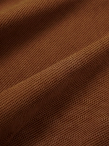 Detailed close-up of high-quality rust red corduroy fabric showing vertical ribbed texture