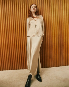 Detail of high-quality champagne satin long skirt with elegant side slit and silk texture