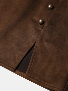 Détail macro d'une jupe en daim avec boutons cuivrés vintage et fente sur l'ourlet