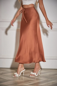 Detail of copper satin midi skirt showing drawstring waist and silky texture on a model