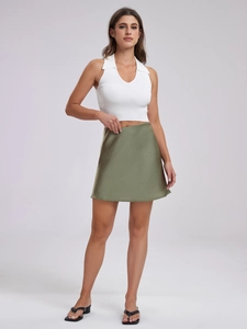Close-up of olive green satin mini skirt paired with a white ribbed halter top in a studio setting
