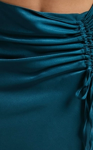 Detail of teal satin skirt showing silky texture, ruching craft, and tie decoration