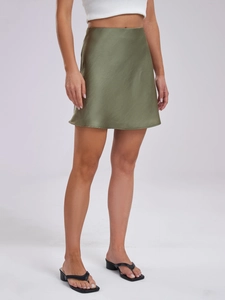 Detail of a grass green satin mini skirt featuring a smooth glossy finish and high waist