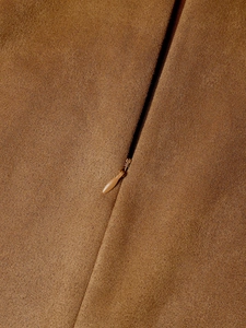 Detail showing the seamless hidden zipper and brown suede texture on a high waist skirt
