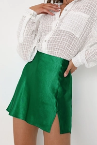 Détail d'une mini-jupe en satin avec fente latérale et chemisier à manches bouffantes