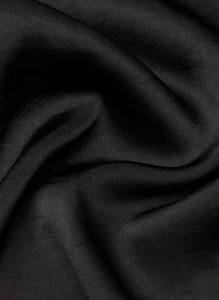 Close-up of black satin skirt fabric showing silky smooth texture and subtle glossy finish