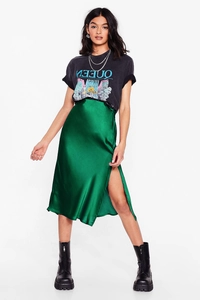 Detail of high-waisted emerald green satin midi skirt with side slit and silky texture