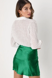 Détail de la jupe midi en satin vert émeraude avec taille haute et texture soyeuse