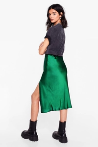 Close-up of emerald green satin midi skirt showing side slit and smooth fabric texture