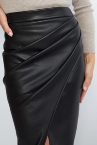 Detail of high-waist black PU leather skirt featuring wrap ruched design and fine texture