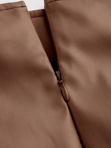 Detail of high waist brown PU leather skirt featuring a seamless hidden zipper closure