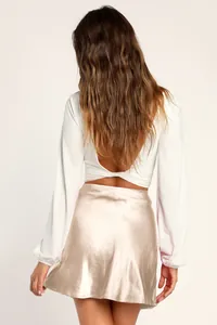 Gros plan sur la jupe midi en satin champagne montrant la texture lisse et la taille haute